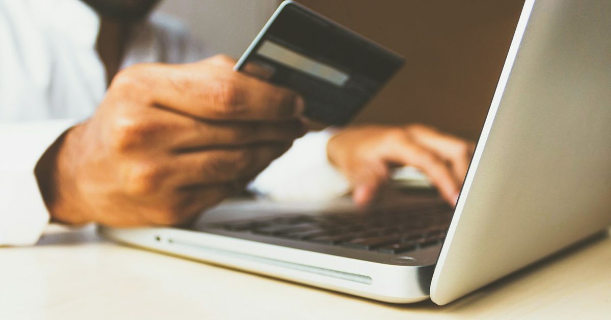 Dizüstü bilgisayarda kredi kartıyla online ödeme yapan kişi